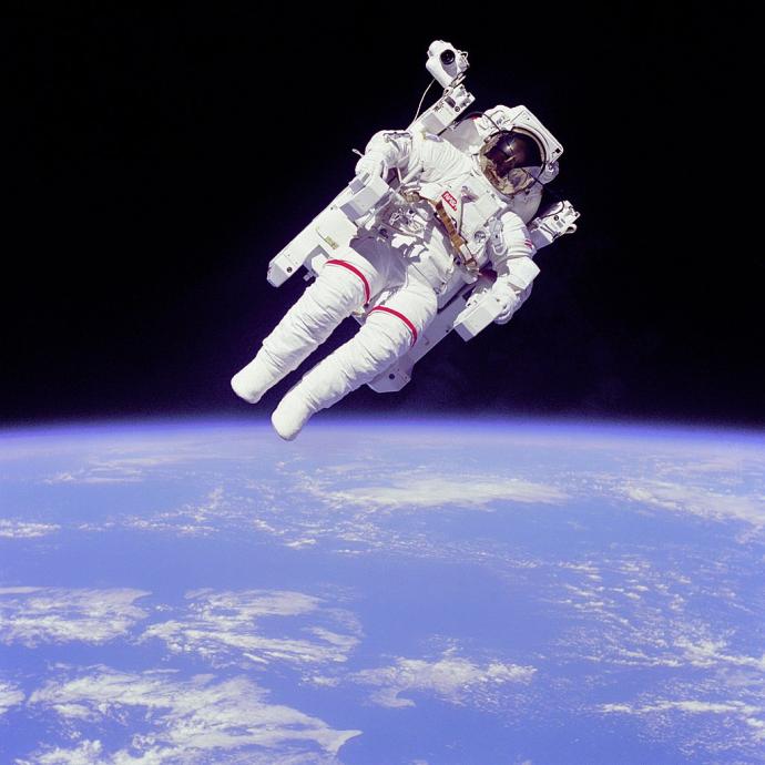 Astronaut floating in space during a spacewalk, using a jetpack with Earth visible in the background.