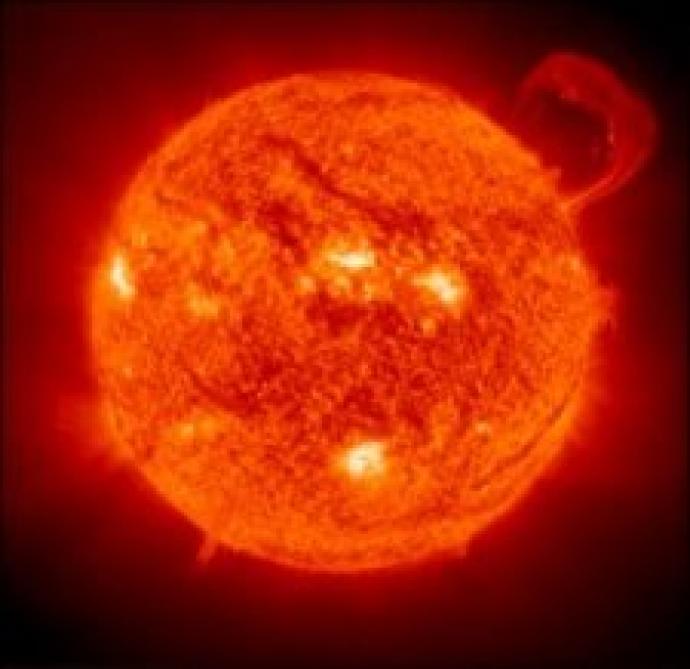 Image of the Sun showing bright, glowing areas and sunspots, with a solar prominence extending from the surface